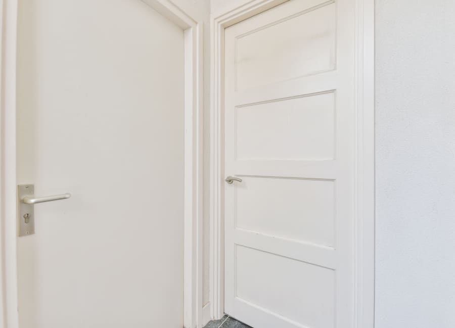 białe drzwi wewnętrzne zamontowane obok siebie w jasnym pomieszczeniu